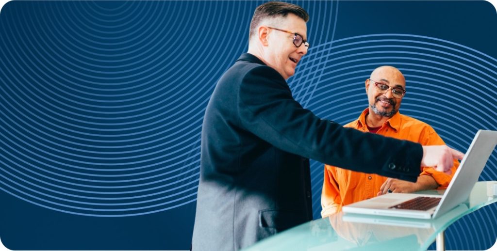 CTO points to his laptop while talking to a coworker.