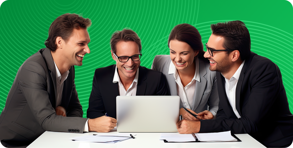 Four tech executives sit grouped together, looking at a laptop in the center of the desk.