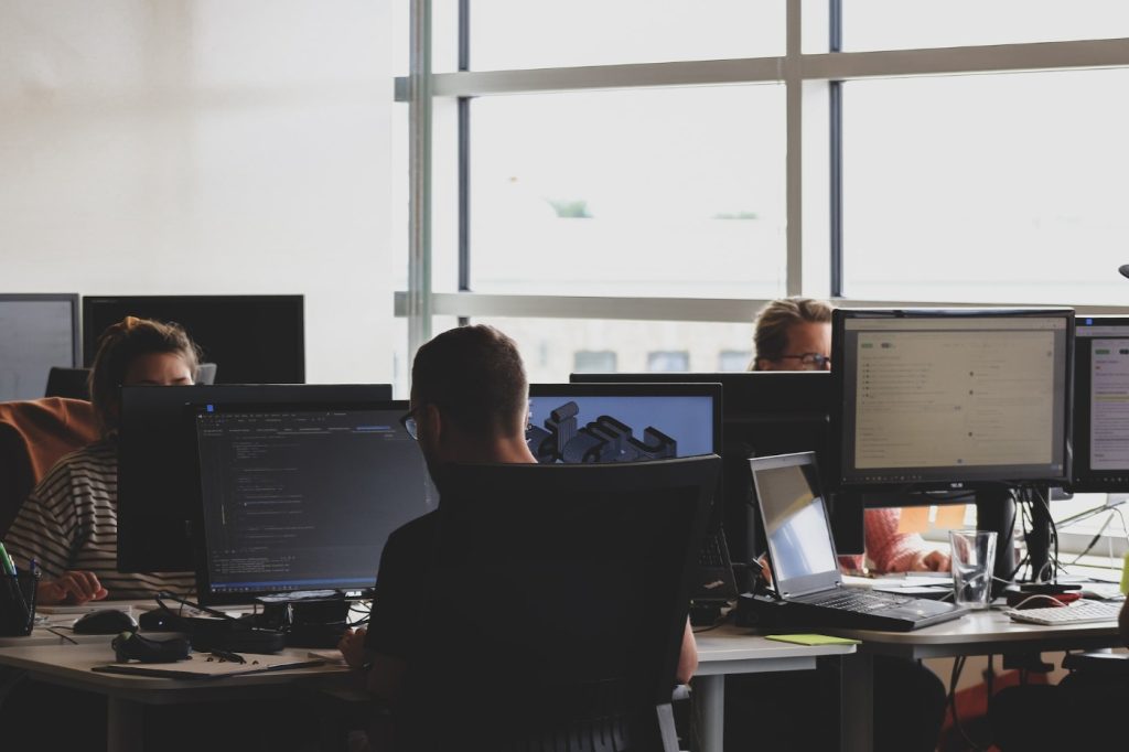 Workers in an office, sitting at a desk in front of a computer.