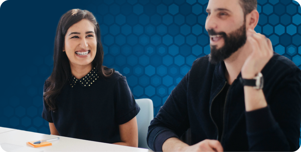 Two coworkers smiling and sitting next to each other in a meeting