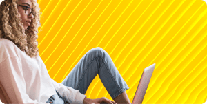 DevOps engineer sits with one leg folded while looking down at her laptop.