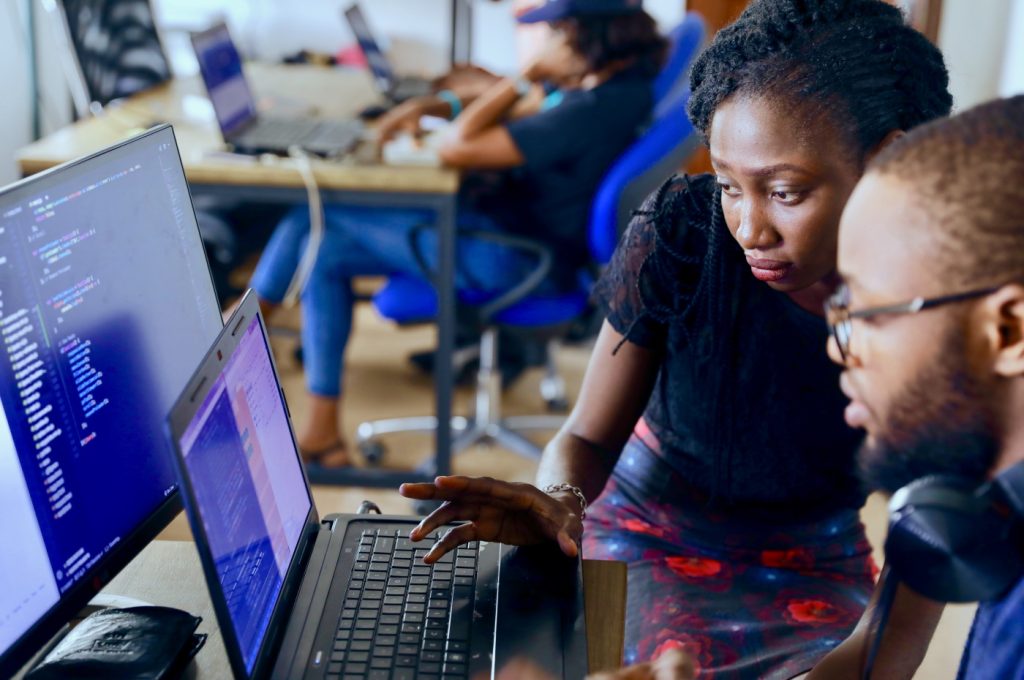A man and a woman gather around a laptop in an office.