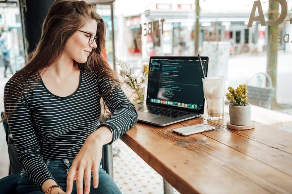 A woman sits near and looks at computer code on a laptop