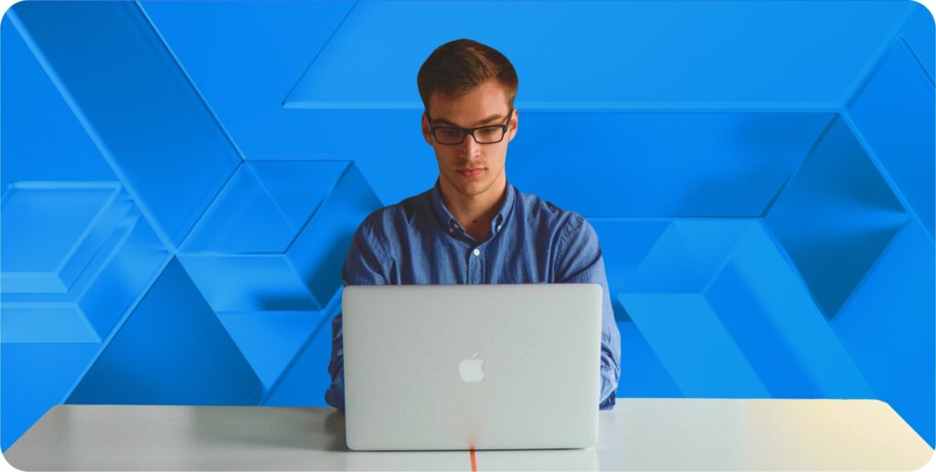 CTO sits in front of a blue geometric background at a laptop.
