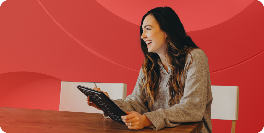 Devops engineer sits at a table smiling and looking to someone off camera.